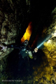   Cave diver descends down moulth fire looking clouds his head swirling tannic river water. water  